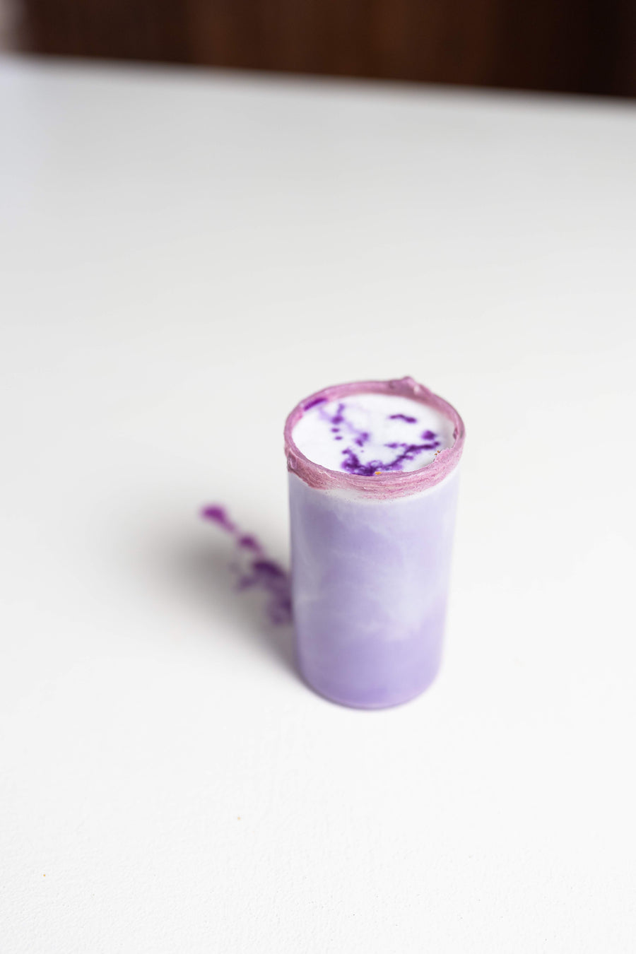 Gelaagd drankje met paarse ube en ijs in een glas