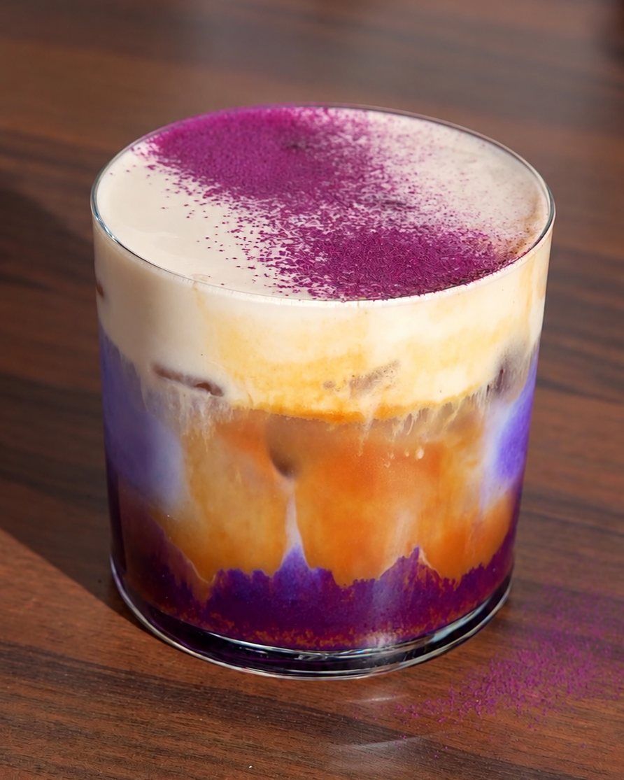 Gelaagde ube koffie: paarse ube onderin, espresso daarboven en melkschuim met ube poeder